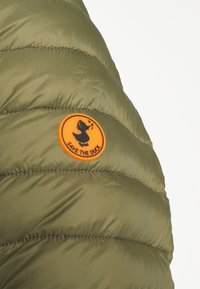 Olijfgroene pufferjack met een gewatteerde textuur op de schouders en een oranje ronde patch met een eend en de tekst "RED DE EEND."