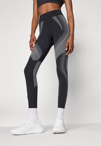 Leggings negre cu accente texturate de gri și modele punctate reflectorizante. Au un talie înaltă și un design ajustat.