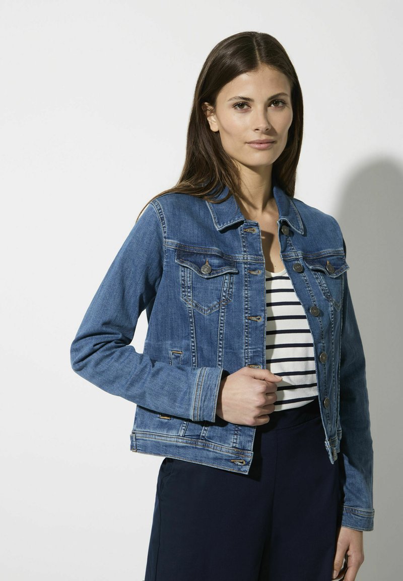 Denimjack met een klassiek ontwerp, blauwe kleur, twee borstzakken, metalen knopen en een gestructureerde pasvorm, over een gestreepte top.