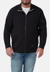 Zwarte zip-up sweatshirt van zachte stof met een grijs gevoerd kraag, geribbelde mouwen, zijzakken en het merkembleem aan de onderkant links.