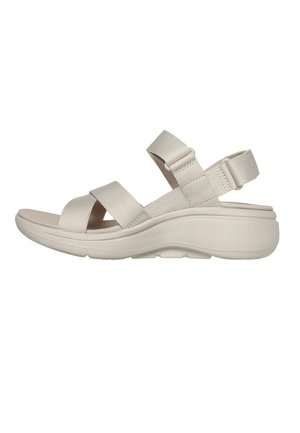 Beige justerbare sandaler med polstret mellemsål, der har brede krydsremme og en rygrem for stabilitet. Letvægtsdesign.