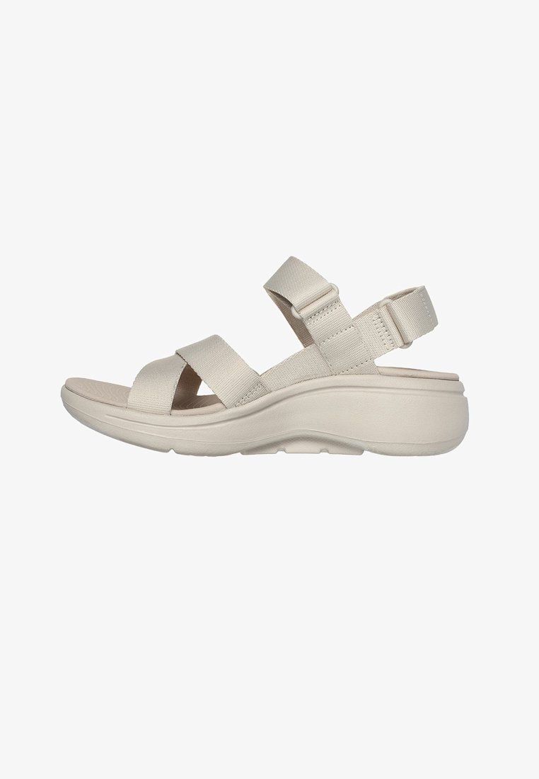 Sandali beige con cinturino regolabile e suola ammortizzata, con ampie cinghie incrociate e cinturino posteriore per maggiore stabilità. Design leggero.