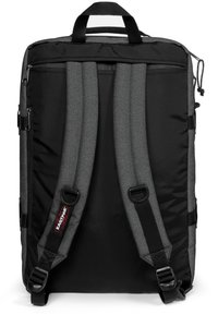 Černý a šedý batoh s polstrovanými šedými popruhy a horním uchytem. Má zipy, hladký povrch a na přední straně je logo štítek.