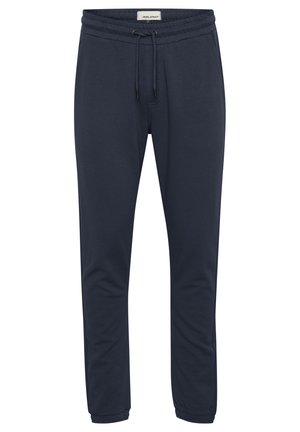 Mørkeblå joggebukser laget av myk stoff, med elastisk midje med snøring og smalnende ben. Glatt tekstur, uten mønstre.