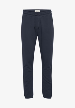 Mørkeblå joggebukser laget av myk stoff, med elastisk midje med snøring og smalnende ben. Glatt tekstur, uten mønstre.