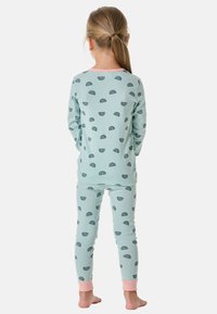 Lichtblauwe pyjama's met een herhalend regenboogpatroon, met lange mouwen en roze manchetten op de broek. Zachte katoenen textuur.
