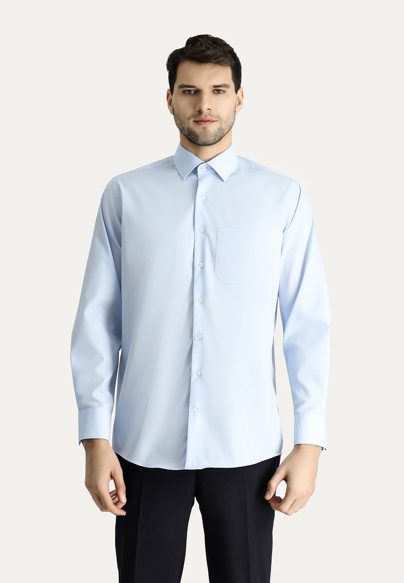Camisa de manga larga de color azul claro, con cuello abotonado, un bolsillo en el pecho, fabricada en tejido suave, corte estándar, acabada con botones blancos.