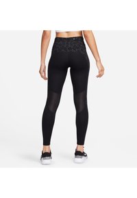 Högmidjade svarta legging med nätpaneler och dekorativ sömnad. Tillverkade av elastiskt tyg för komfort under fysiska aktiviteter.