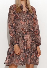 Dunkel gemustertes Kleid mit Paisley-Muster, langen Ärmeln, einem gerafften Saum und einem geknöpften Kragen; zeigt Schattierungen von Braun, Rosa und florale Akzente.