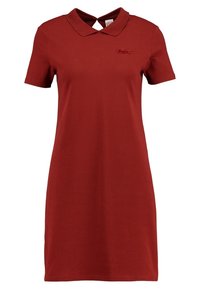 Červené polo šaty z bavlny, s klasickým límečkem, krátkými rukávy a malým logem na levém prsu. Hladká textura.