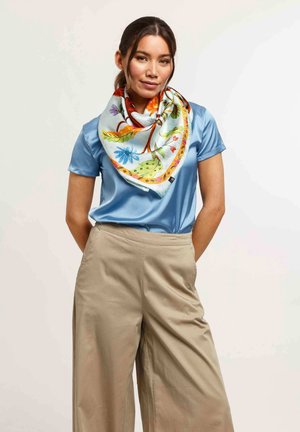 Multicolored silk scarf tied around the neck, featuring floral and leaf patterns on a light blue background. Smooth texture, vibrant colors.