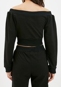 Schwarzes, kurzes Sweatshirt mit schulterfreier Gestaltung, langen Puffärmeln, gerippten Bündchen und Saum, hergestellt aus weichem Stoff.
