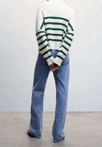 Striped sweater in cream and green with a cropped design, paired with light blue, high-waisted jeans featuring a relaxed fit.