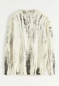 Pull en tricot crème avec un motif abstrait de coups de pinceau noirs. Il possède un col rond, des poignets et un ourlet côtelés, offrant une coupe décontractée.