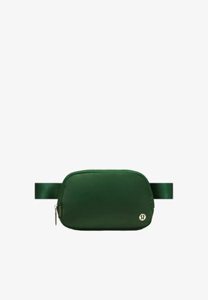 Dunkelgrüne rechteckige Bauchtasche mit verstellbarem Gurt, Reißverschluss und kleinem rundem silbernem Logo in der vorderen unteren rechten Ecke.