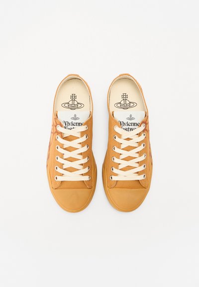 Tan canvas sneakers med hvide snørebånd, rund tå og kontrasterende trykte detaljer. Logo trykt på indersålerne, minimalistisk design.