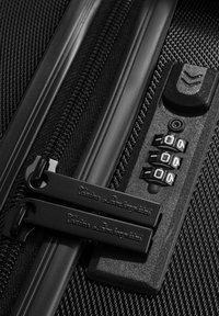 Valigia nera con cerniera a doppio estrattore, tessuto testurizzato, lucchetto a combinazione con quadranti numerati, design elegante e senza marchi visibili.