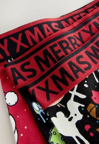 Patterned fabric featuring a mix of bright colors with festive designs, including cartoon elements; red elastic waistband with "MERRY XMAS."