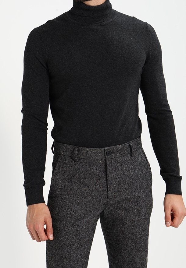 Zwarte gebreide coltrui met lange mouwen, gedragen met hoog-waist, gemusterde grijze broeken. Glad textuur en aansluitend ontwerp.