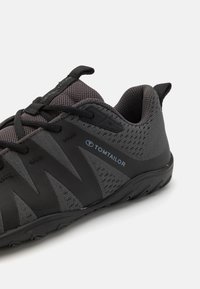 Scarpe da ginnastica nere con una tomaia in mesh traspirante, dettagli neri texturizzati e una suola in gomma flessibile con un motivo antiscivolo.