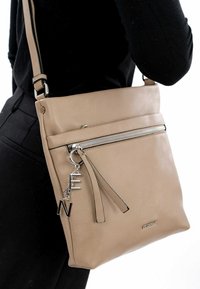 Beige leather crossbody bag with a zippered front pocket, detachable charm with letters, and an adjustable strap. Smooth texture, minimalist design.