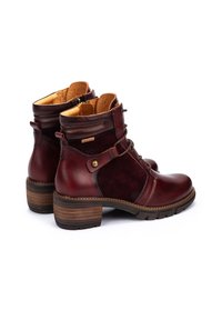 Las botas hasta el tobillo de un burdeos oscuro presentan una combinación de cuero liso y ante, con una punta redonda, tacón de bloque de madera y un diseño de cordones.