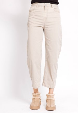 Beige cropped pants paired with light tan fur-lined ankle boots on a white background.