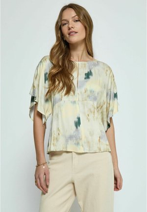 Crème tie-dye top met groene en grijze accenten, korte vlindermouwen, een ronde halslijn en een subtiele voorkantsplit. Gepaard met beige broek.