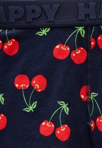 Σκούρο μπλε ύφασμα με σχέδιο ζεύγη κόκκινων κερασιών και πράσινα κοτσάνια, επάνω από μια φαρδιά ζώνη μέσης με ανάγλυφα γράμματα που γράφουν "HAPPY".