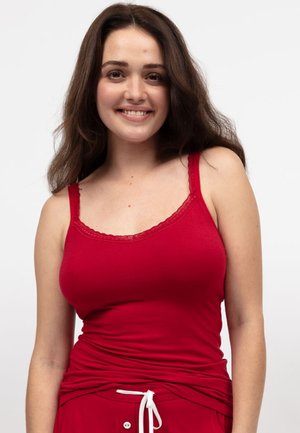 Canotta rossa in cotone con spalline regolabili e bordo in pizzo. Design morbido e aderente con scollatura rotonda. Abbinata a pantaloni rossi con coulisse.