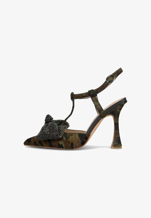 Spitze Pumps mit Camouflage-Muster, ausgestattet mit einer strukturierten schwarzen Schleife und verstellbarem Knöchelriemen. Der Stiletto-Absatz ist durchsichtig.