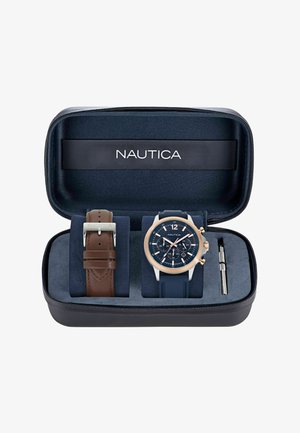 Zestaw zegarka Nautica w czarnym etui na suwak. Zawiera zegarek w kolorze granatowym na silikonowym pasku z różowozłotymi akcentami oraz brązowy skórzany pasek. W zestawie narzędzie do regulacji.