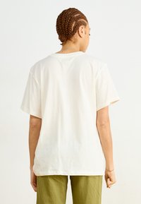 Korte mouwen, crèmekleurig t-shirt met een relaxte pasvorm, ronde hals en zachte katoenen textuur. De achterkant heeft geen graphics of patronen.