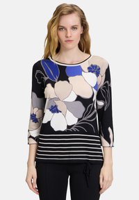 Blusenshirt mit floralem Muster und Dreiviertelärmeln in Schwarz, Beige und Blau, mit horizontalen Streifen am Saum und rundem Halsausschnitt. Aus weichem Stoff hergestellt.