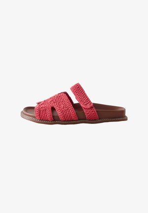 Brown flat sandal with two textured coral pink straps, one wide front strap with cutouts and one adjustable ankle strap.