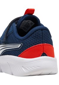 Zapatilla de malla azul marino con acento rojo en el talón, suela blanca y detalles laterales. Cuenta con un collarín acolchado y una lengüeta en la parte trasera para facilitar el calzado.