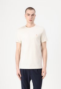 Tricou crem cu mânecă scurtă, confecționat dintr-un material moale, având un mic logo portocaliu "II" pe pieptul stâng și un gât rotund.