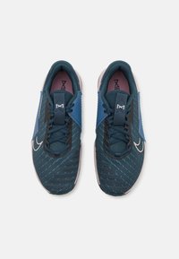 Sportliche Schuhe mit einem dunkelblauen Mesh-Obermaterial, schwarzen und blauen Akzenten, Schnürdesign und einer hellen Sohle. Verfügt über ein Logo an der Seite.