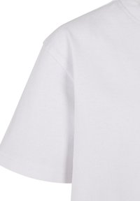 Nærbilde av en ensfarget hvit t-skjorte med korte ermer som viser detaljer på skulder og ermer mot en hvit bakgrunn.