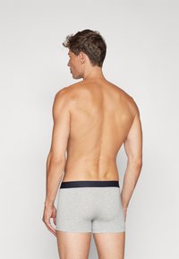 Herren graue Boxershorts mit einem kontrastierenden marineblauen Bund, aus weichem Baumwollstoff gefertigt, mit einem körpernahen Schnitt und glatter Textur.