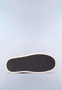 Suela de zapato con una superficie de goma negra texturizada y borde beige, que presenta un patrón ondulado y el logo en relieve "NAPAPIJRI."