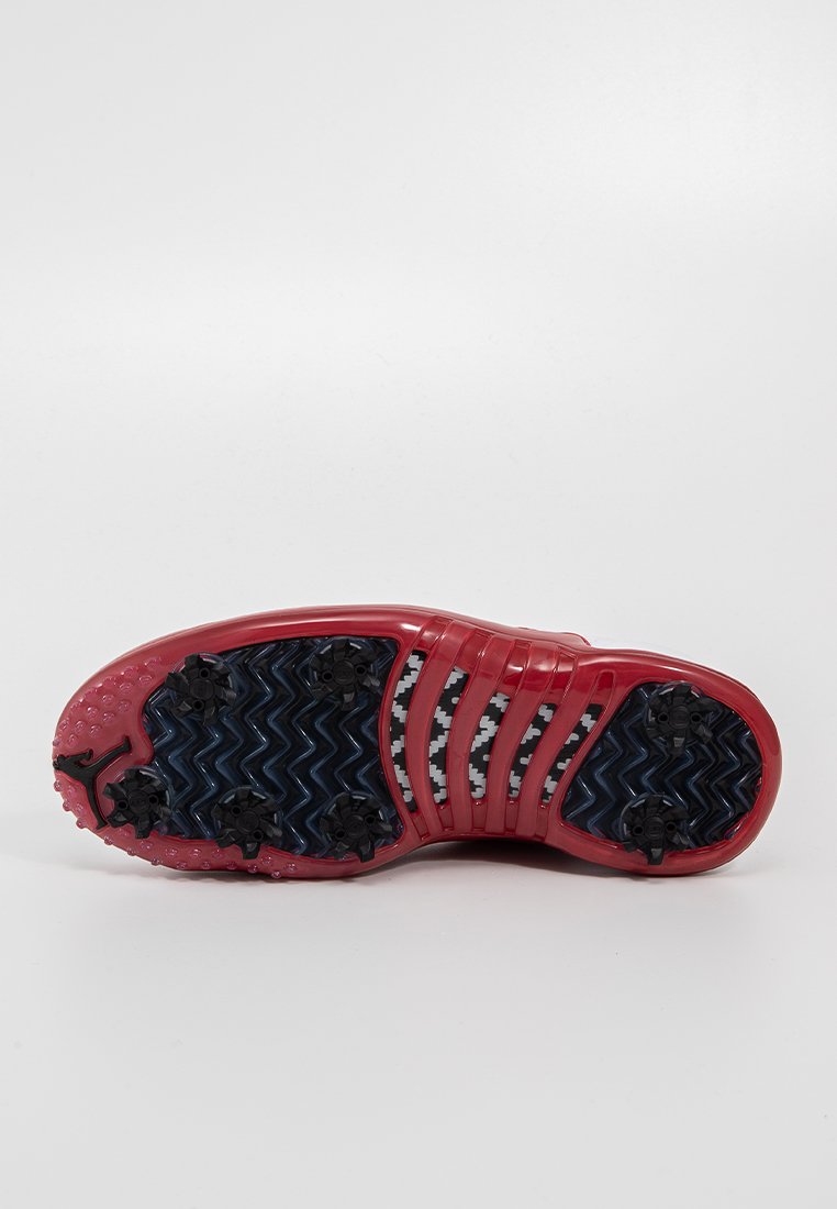 Czerwona podeszwa sportowego buta z teksturowanymi niebieskimi i czarnymi wzorami, z zygzakowymi rowkami i sześcioma czarnymi wypustkami dla lepszej przyczepności.
