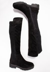 Schwarze Stiefel bis zum Knie aus mattem Wildledermaterial mit einem strukturierten schwarzen Glitzerpanel und einem seitlichen Reißverschluss, robuste Sohle mit einem Griffmuster.