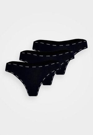 Tanga de algodão preta com um design sólido; possui cinturas elásticas estampadas com a palavra "GUESS" em branco. Três pares estão expostos.