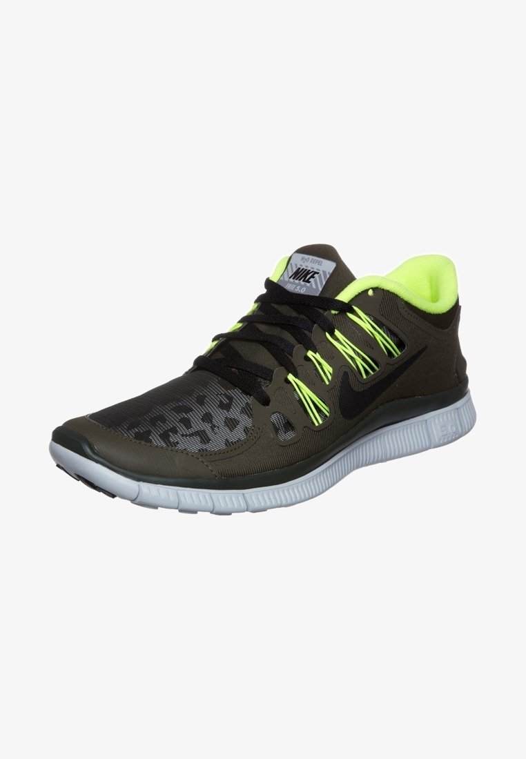 Chaussure de course Nike vert foncé et noir avec lacets et doublure jaune néon, semelle blanche flexible et zone des orteils à motif.