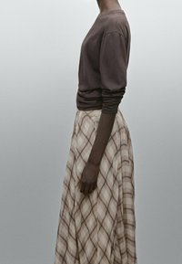 Braunes Langarmshirt kombiniert mit einem karierten, bodenlangen Rock in Beige- und Hellbrauntönen. Glatter Stoff mit weicher Textur und schönem Fall.