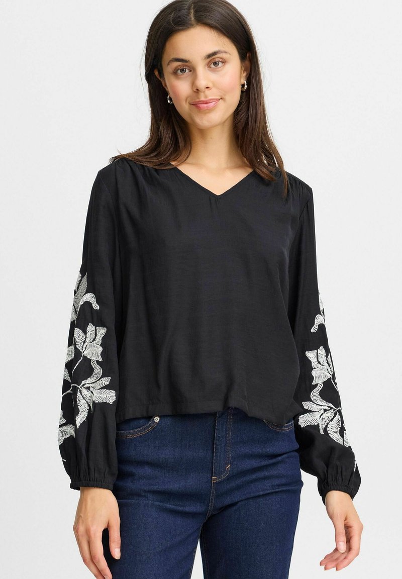 Blusa nera con scollatura a V e maniche lunghe, caratterizzata da ricami floreali bianchi sulle maniche. Tessuto leggero con una vestibilità comoda.