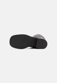 Talpa de cizme din piele neagră cu o textură netedă, vârful rotund și un toc ușor. Prezintă un design embosat și un model de prindere din cauciuc.