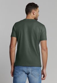 Groene T-shirt met korte mouwen en ronde hals, met een gladde textuur en een slim fit, gecombineerd met lichtblauwe spijkerbroek.