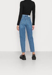 Ljusblå jeans med rak benpassform, hög midja och två bakfickor. Matchas med svarta platåskor och en figurnära svart långärmad topp.